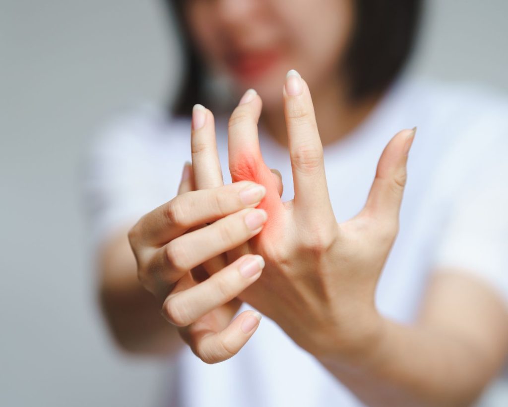 Mujer señalando dolor articular en sus dedos de la mano
